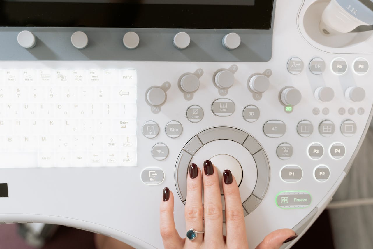 Hand operating a high-tech ultrasound control panel in a medical facility.